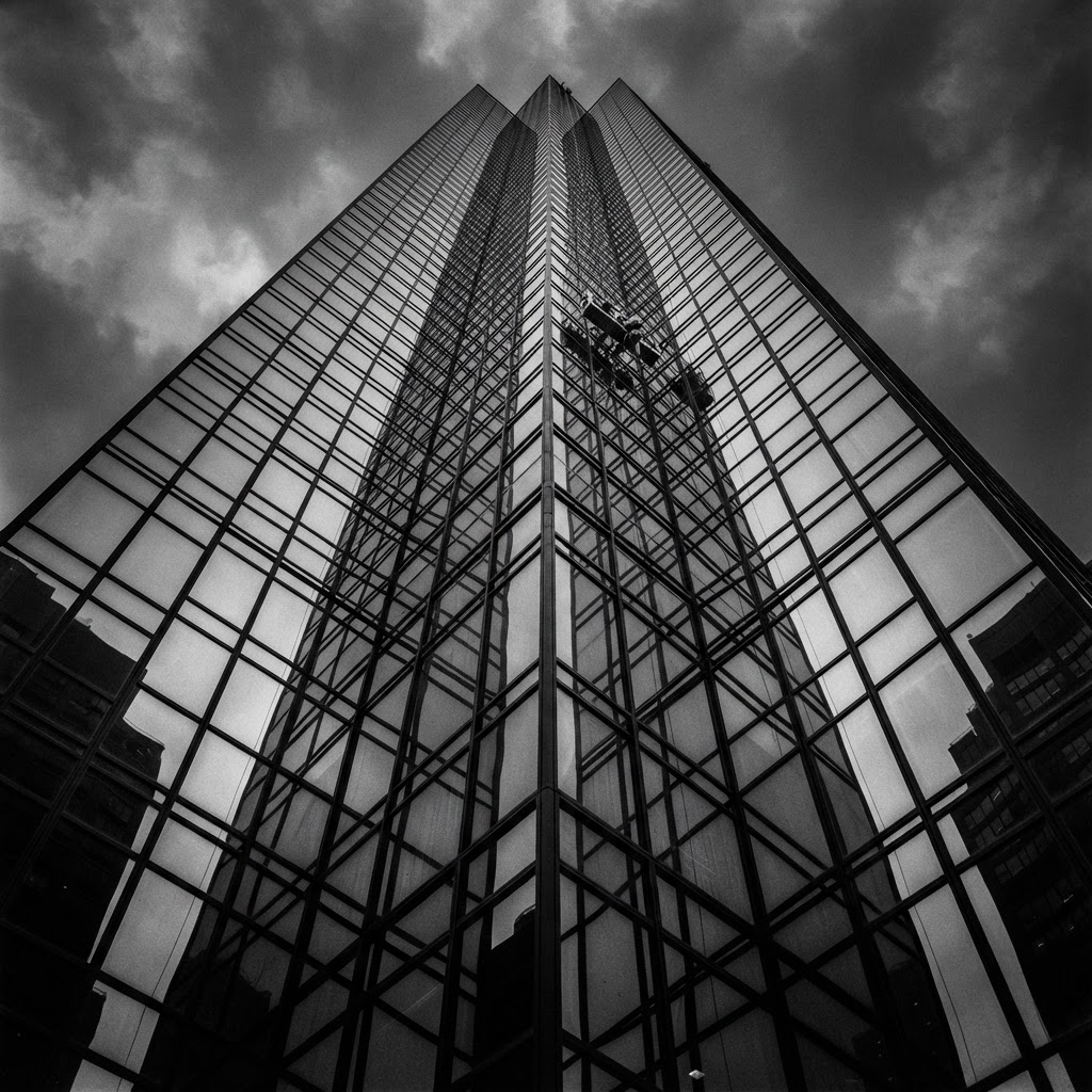 Window cleaner servicing the glass facade of a modern commercial building